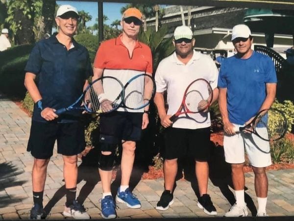 four men holding a tennis racket